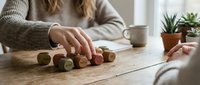 Woman playing with wooden toy train on rustic table in cozy home interior with plants and coffee cup creating peaceful domestic scene.