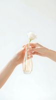Two hands gently holding glass vase with single white rose on clean neutral background symbolizing love care and tenderness in minimalist style.