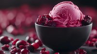 Pink raspberry ice cream scoop in black ceramic bowl garnished with fresh berries against dark background with bokeh lights, selective focus macro shot.
