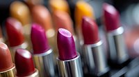 Colorful array of metallic lipstick tubes featuring vibrant shades from burgundy to pink, arranged in line with soft focus bokeh effect. For beauty and cosmetic marketing.