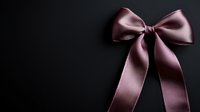 Elegant dusty rose satin bow ribbon isolated on black background, luxurious gift wrapping and decoration element for special occasions and holidays.