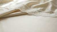 Ivory lace trim with delicate floral embroidery on cream silk fabric, perfect for wedding dress design, bridal gown embellishment, and luxury textile projects.