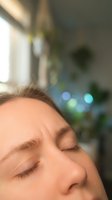 Peaceful middle-aged Caucasian woman with closed eyes relaxing in bright modern home interior with soft bokeh lights creating serene wellness atmosphere.