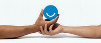 Two hands gently passing blue smiley face symbol representing customer satisfaction, teamwork and positive communication in business relationships.