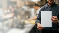 Male worker in dark work shirt holding blank white sign or clipboard on industrial construction site background.