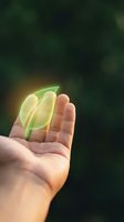 Glowing green leaves floating above open palm symbolizing environmental protection, sustainability and eco-friendly growth concepts.