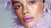 Close up portrait of young mixed race woman with lilac feathers and pink lips wearing artistic makeup against light background. Professional beauty photography.