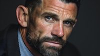 Mature Caucasian man with intense gaze, beard and styled hair against dark background, conveying determination and confidence for business or lifestyle content.