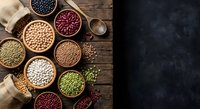 Assorted legumes and beans in wooden bowls on rustic table with burlap sack and wooden spoon for healthy cooking and nutrition concepts.