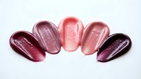 Glossy lip gloss swatches in pink and berry tones arranged in arc formation on white background for beauty and cosmetics marketing materials.