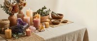 Spa wellness setup with burning candles, crystals, dried flowers and natural elements on linen table for relaxation and meditation rituals.