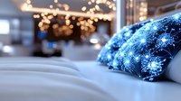 Cozy winter bedroom interior with decorative blue snowflake pattern pillow on white bedding and warm fairy lights creating magical holiday atmosphere.