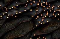 Luxury dark fabric with golden beads scattered across textured surface, creating elegant pattern for fashion, textile design, and luxury product backgrounds.