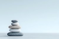 Balanced stack of smooth zen stones on light blue background creating harmony and tranquility, minimalist composition for wellness and meditation.