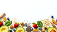 Healthy superfood ingredients frame on white background with avocado, berries, nuts, seeds and oats for nutritious meal planning and clean eating.