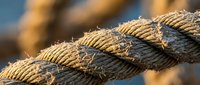 Thick braided rope with natural fiber texture in warm sunlight, showing detailed weave pattern and rustic maritime nautical design for outdoor adventure concepts.