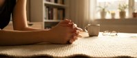 Woman practicing yoga meditation in sunlit room with clasped hands on mat for mindfulness wellness and spiritual relaxation at home.