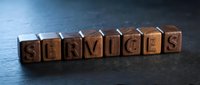 Wooden letter blocks spelling SERVICES on dark textured surface, conveying business support and customer care concepts for marketing materials.