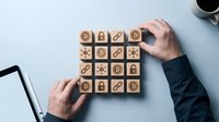 Businessman arranging wooden blocks with bitcoin, blockchain, and security icons on a desk, symbolizing cryptocurrency and digital finance concepts.