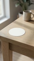 Minimalist white round coaster on natural wood table with ceramic mug in bright modern interior for home decor and dining accessories.