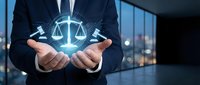 Professional businessman holding glowing digital scales of justice hologram in modern office representing legal technology and law firm services.