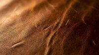 Rich brown leather texture with natural grain patterns and warm lighting for luxury crafts and fashion design projects.