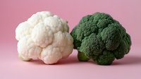 Fresh white cauliflower and green broccoli heads on pink background for healthy cooking and nutrition concepts.