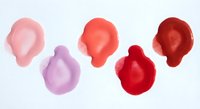 Colorful nail polish drops in pink red purple shades isolated on white background for beauty cosmetics and manicure design projects.