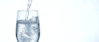Fresh water pouring into clear glass with bubbles and splash on white background for hydration and refreshment concepts.