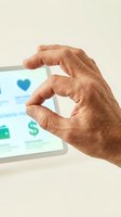 Senior adult hand making heart shape gesture while holding tablet with healthcare app interface displaying heart icon and dollar sign symbol.