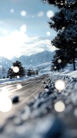 Snowy mountain road with pine trees and falling snowflakes creating bokeh effect against blue sky and distant peaks.