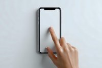 Female hand touching blank smartphone screen on light gray background, demonstrating mobile device interaction for app interface mockups.