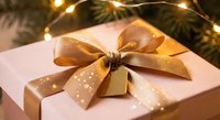 Elegant gift box with golden polka dot ribbon bow under warm fairy lights. Holiday present wrapping for Christmas celebrations and festive occasions.