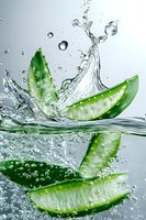 Fresh cucumber slices splashing in clear water with dynamic water drops and bubbles creating energetic motion effect. Great for healthy lifestyle advertising.