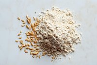 Oat grains and freshly milled oat flour on marble background, showcasing whole grain transformation for healthy baking and cooking.