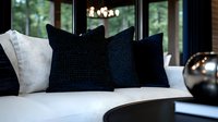 Elegant white sofa with contrasting black and white throw pillows in modern living room interior. Soft natural lighting through windows creates luxurious ambiance.