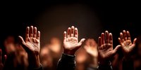 Diverse group of people raising hands up in warm lighting during community gathering or worship service with bokeh background effects.