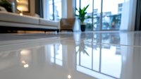 Glossy reflective floor in modern minimalist interior with natural lighting through large windows. Blurred furniture and plants create depth and luxury atmosphere.