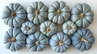 Blue-gray pumpkins arranged in rows on white background, decorative gourds with natural stems showing seasonal autumn harvest and modern farmhouse style.
