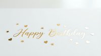 Happy Birthday gold foil lettering on white background with scattered hearts and stars, elegant greeting card design for celebration.