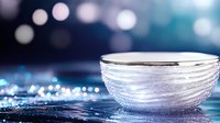 Elegant glass bowl with rippled texture on reflective surface against blurred bokeh background in blue tones, creating luxurious ambiance.