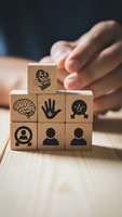 Wooden blocks with healthcare icons stacked in pyramid formation with hands protecting structure representing medical insurance and wellness concepts.