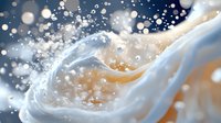 Flowing white liquid with golden splashes and sparkles on dark blue background creates dynamic abstract composition with light bokeh effect and waves.
