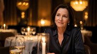 Elegant mature businesswoman dining alone in upscale restaurant with warm candlelight and luxurious ambiance for fine dining and hospitality concepts.