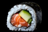 Fresh salmon and cucumber sushi roll with white rice and nori seaweed wrap on black background, macro food photography showing texture and ingredients.