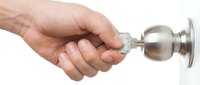 Male hand turning stainless steel door knob on white background, isolated for design use on websites, apps, and marketing materials.