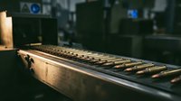 Professional mixing console with faders and controls in recording studio environment with warm lighting and blurred background equipment.