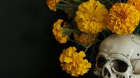 Day of the Dead celebration with decorated skull and vibrant orange marigold flowers on dark background for traditional Mexican holiday festivities.