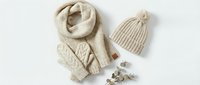 Cozy beige knitted winter accessories set with cable pattern scarf, pom pom hat and mittens on white background for seasonal fashion and warmth.