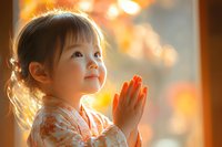 Young Asian girl with clasped hands in prayer position illuminated by warm sunset light, wearing floral pattern dress, expressing pure innocence and hope.